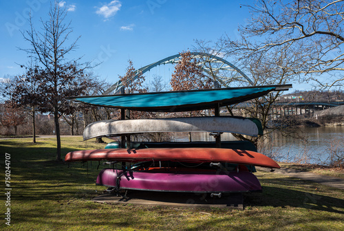 Photography Colorful canoes with Birmingham Bridge across the Allegheny River and a blue sky seen from Three Rivers Heritage Trail, Pittsburgh, on an early sunny spring day