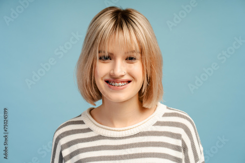 Beautiful, smiling young woman with blond hair, with braces, smiling, looking at camera