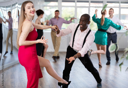 Positive woman and man dancing foxtrot in pair during group dance party