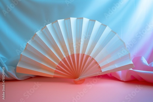 Pastel paper fan opened against a soft  light blue and pink background.