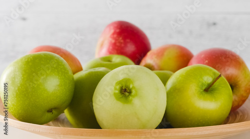 Red and green apples on a wooden plate
