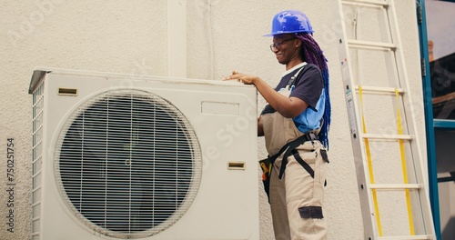 Efficient repairman starting work on defective air conditioner, using handheld drill to disassemble condenser metal coil panel. Experienced mechanic dismantling hvac system to check for dirt