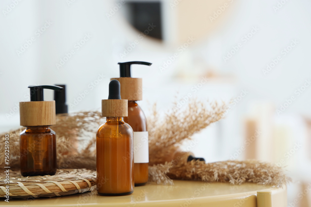 Cosmetic bottles with pampas grass on table in bathroom, closeup
