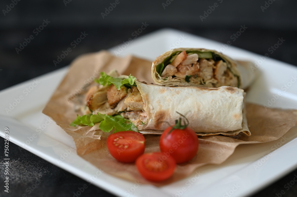Shawarma, fresh roll of lavash tortilla on a white plate with tomato cherry Shawarma, fresh roll of lavash tortilla on a white plate with tomato cherry