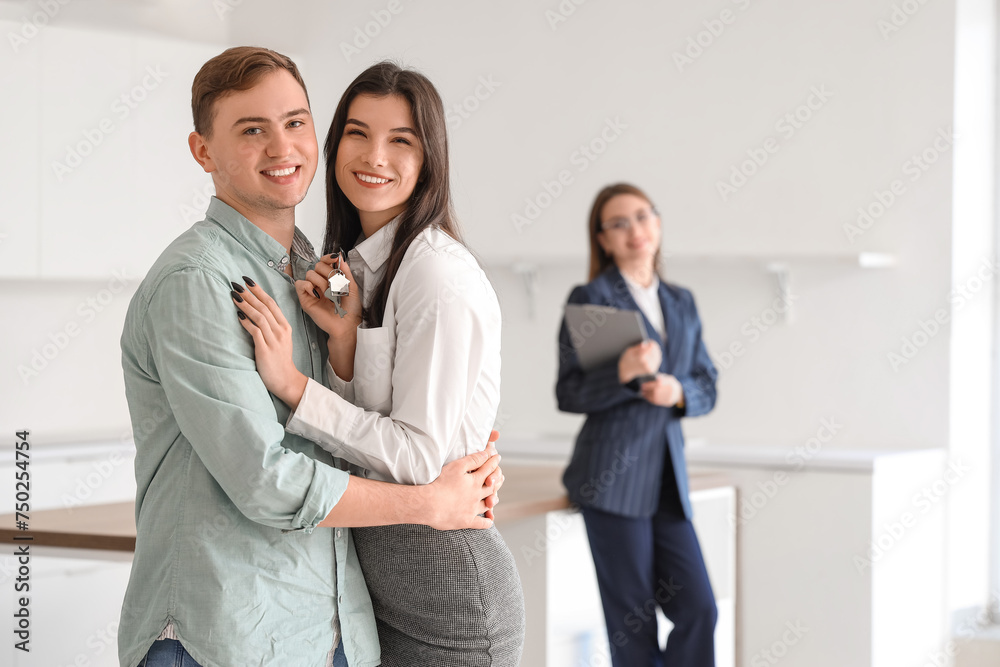 Happy young couple with keys from their new flat hugging in kitchen Happy young couple with keys from their new flat hugging in kitchen