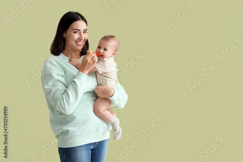 Young woman feeding her little baby on green background