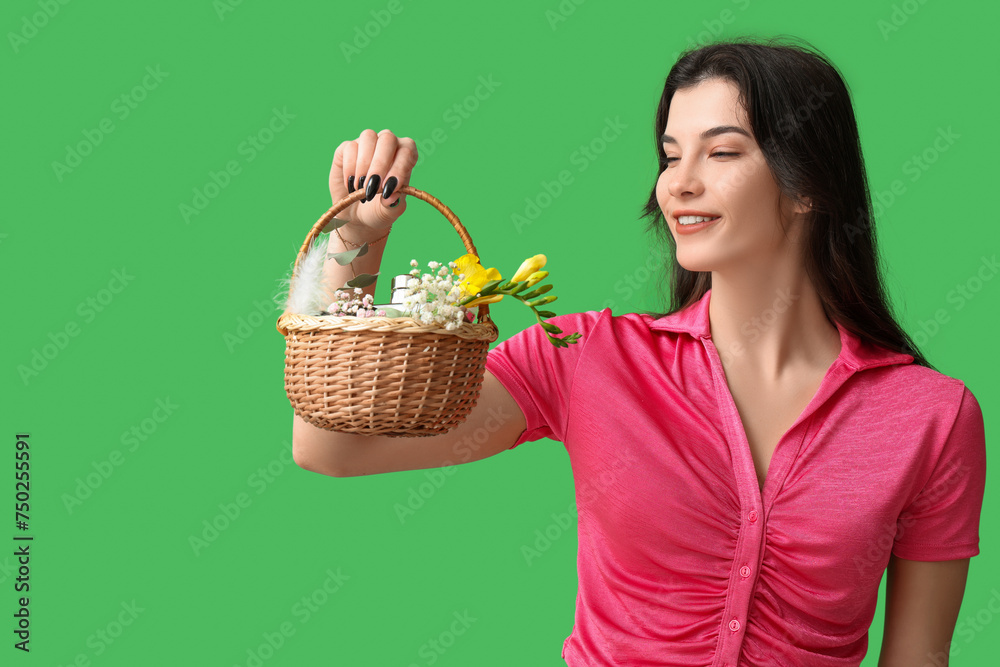 Pretty young woman holding wicker Easter basket with cosmetics on green background Pretty young woman holding wicker Easter basket with cosmetics on green background