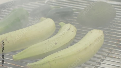 Grilled Banana on fire, latin american vegan grill with avocado and pepper, thai or Ecuadorian Street food. African traditional food on grill. 