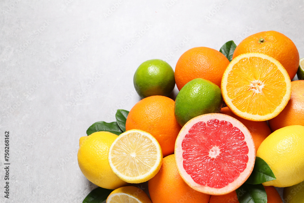 Pile of different fresh citrus fruits and leaves on grey textured table, flat lay. Space for text Pile of different fresh citrus fruits and leaves on grey textured table, flat lay. Space for text