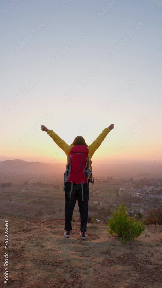 woman raises her hands up standing on the top of a mountain against beautiful sunrise sky. Watching the sunrise with beautiful landscape woman raises her hands up standing on the top of a mountain against beautiful sunrise sky. Watching the sunrise with beautiful landscape