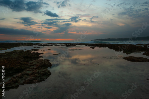 Puesta de sol playa con reflejos en el agua con rocas y oleaje en Sawarna  Labak Regency  Banten. Java  Indonesia