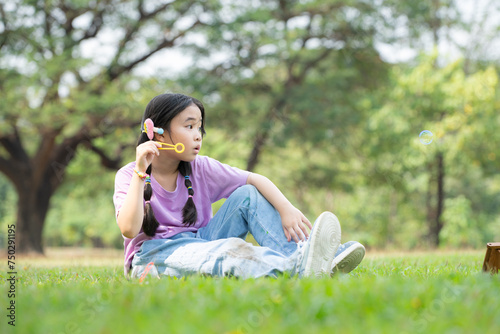 Girl sitting in the park with blowing air bubble  Surrounded by greenery and nature