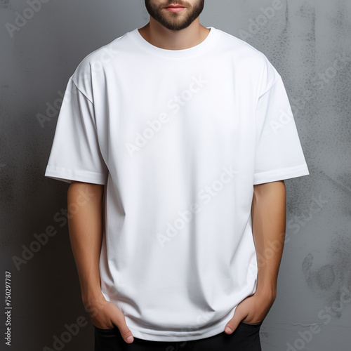 Man in white oversize t-shirt on gray wall for clothing mockup