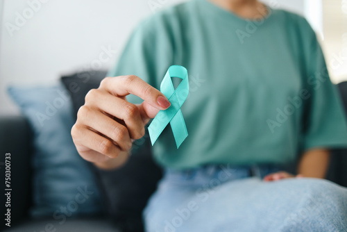 Obraz na plátně Close-up teal awareness ribbon holded by woman hands to support cancer survivor