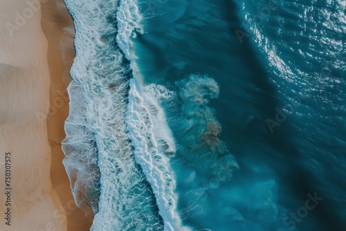 This aerial view showcases a sandy beach meeting the vast expanse of the ocean. Waves crash against the shore, creating white foam as seagulls soar overhead.