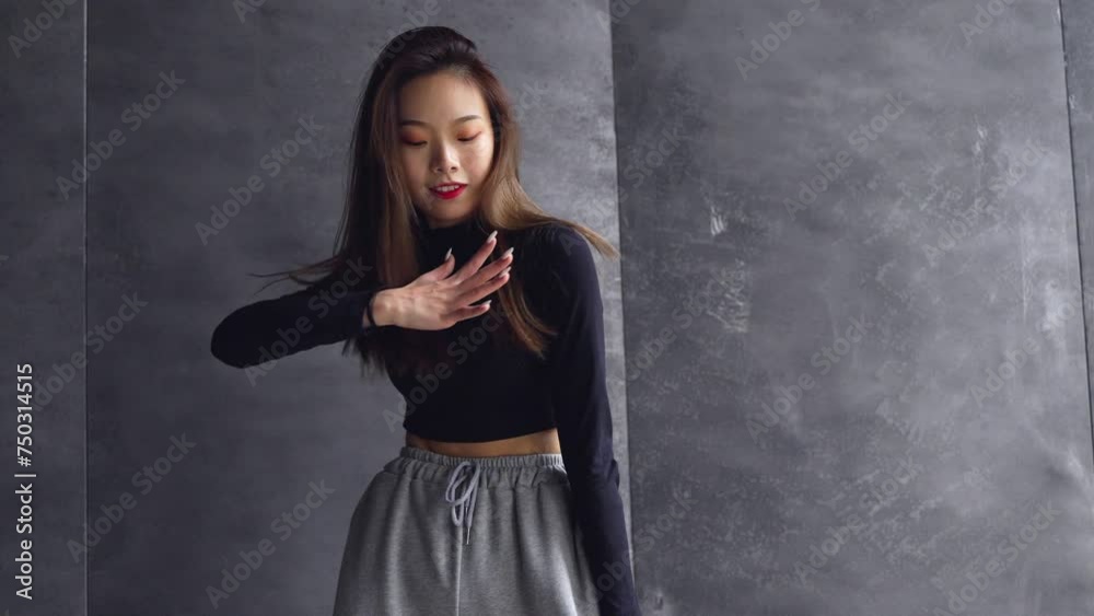 slow motion of young asian woman dancing against gray wall young people street dance youth culture