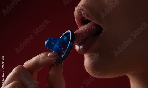 Tongue licking condom. Mouth of sensual girl with condom. Open mouth and sexy lips, lick condom. Condom in mouth of sexy women. Protection, safe sex and Contraceptive concept.