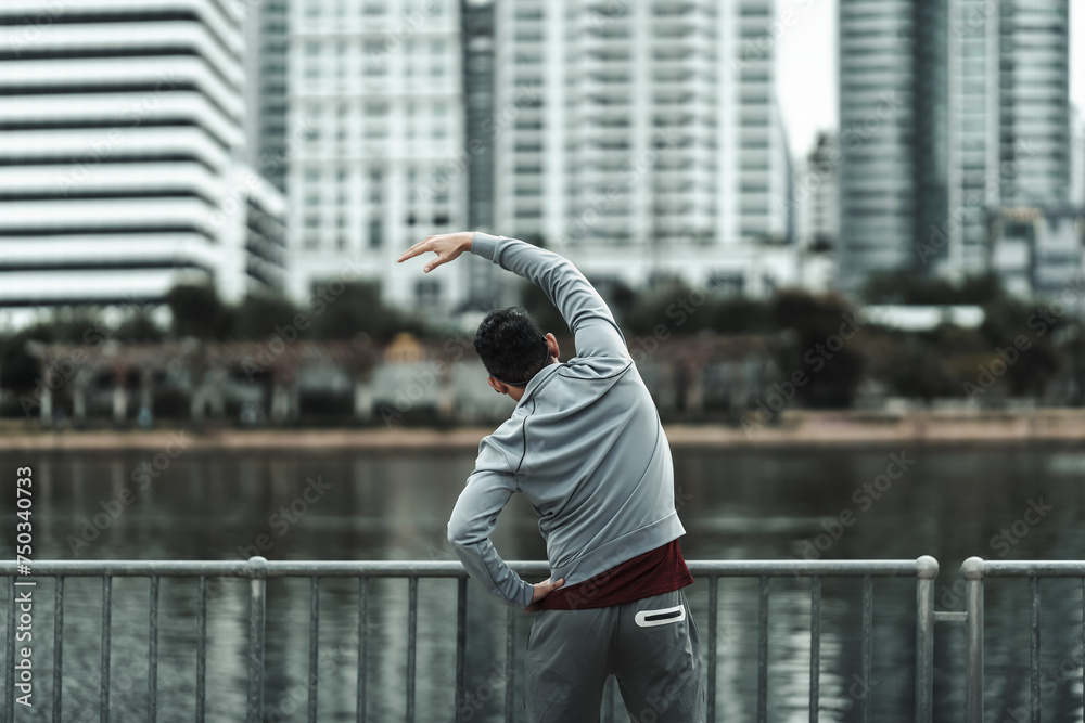 A man stretching his muscle  in the city center park before  cardio workout, running.  Health and Lifestyle in big city life concept. - obrazy, fototapety, plakaty 