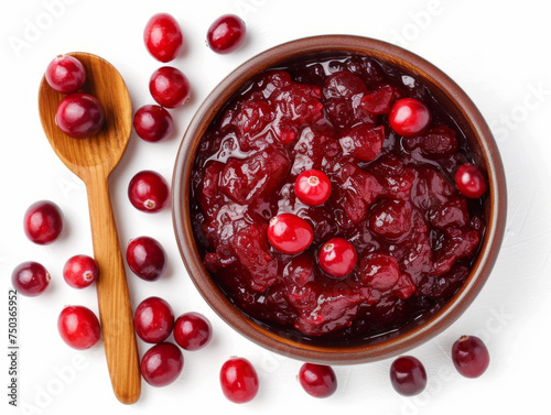 Cranberry sauce with a wooden spoon in a bowl with whole cranberries, top-down view on a white background. The concept of sweet and spicy seasoning for design and printing photo