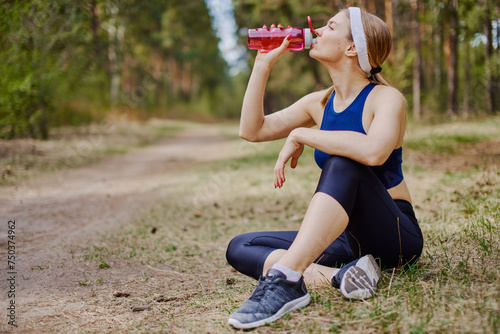 Fototapeta Naklejka Na Ścianę i Meble -  Sportive woman drinking water during outdoors workout