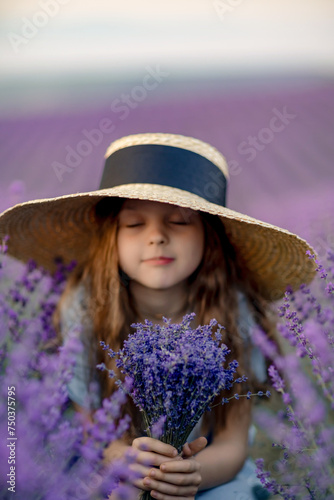 Girl lavender field in a blue dress with flowing hair in a hat stands in a lilac lavender field