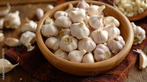 Heads of garlic in a wooden bowl on a wooden table.