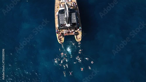 man jumps from boat into water, catamaran in blue sea water, beautiful bay on an island, tenerife, boat, summer, drone photo