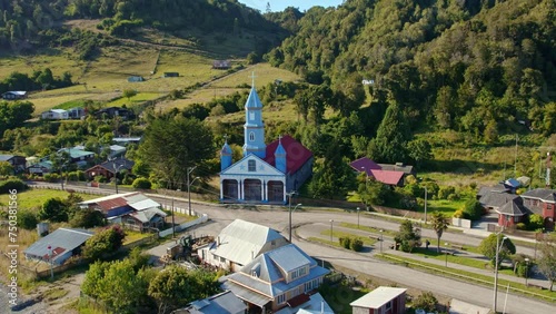 Tenaun village with iconic blue unesco heritage church in chiloe, sunny day, aerial view photo