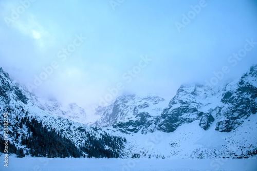 Winter dawn in mountains. Beautiful winter landscape with mountain lake and snowy hills. Morskie oko lake. Lake in tatra mountains in winter at dawn. Poland, Zakopane. © WellStock