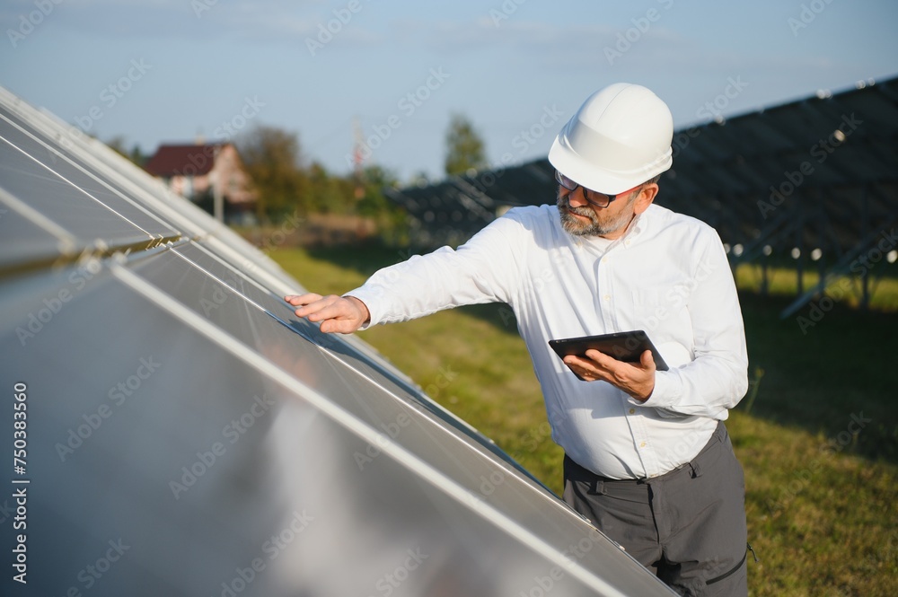 Engineer man in helmet in the field of solar panels