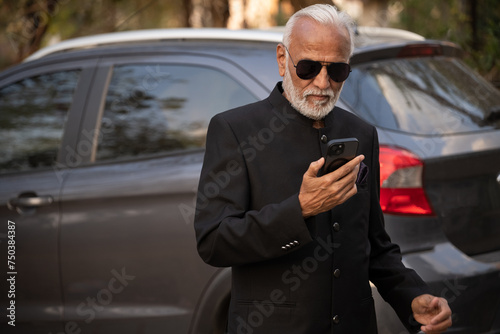 Lifestyle shot of senior Indian man wearing a suit working on a phone Digital India and digitally literate citizens © Ojas