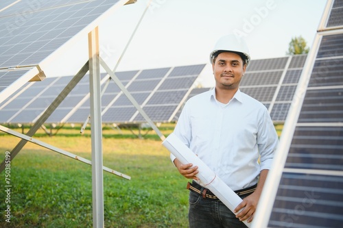 Portrait of Young indian male engineer standing near solar panels, with clear blue sky background, Renewable and clean energy. skill india, copy space © Serhii
