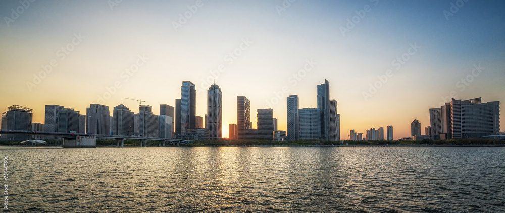 Obraz premium Panoramic Sunset View Over City Skyline and Calm River