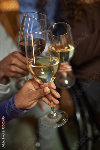 Vertical closeup of hands holding wine glasses and toasting while celebrating holiday together