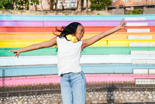Fotografie Carefree afro woman with headphones enjoys a moment of freedom by a pride wall