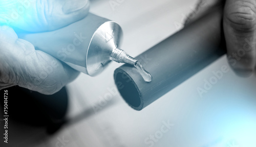 Plumber applying glue on pvc pipe; light effect