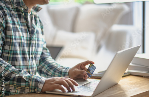 Close Up man hands holding credit card using online shopping with laptop, Online payment at home or office, internet banking, future lifestyle ideas for spending or entrepreneurs in ordering products © ART STOCK CREATIVE