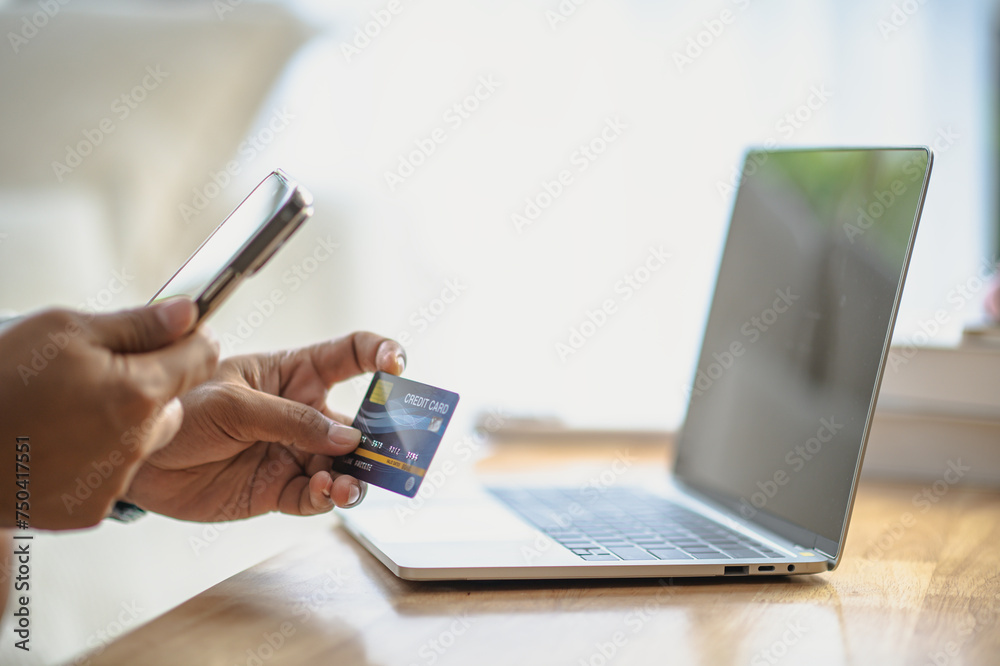 Fototapeta premium Close Up man hands holding credit card using online shopping with laptop, Online payment at home or office, internet banking, future lifestyle ideas for spending or entrepreneurs in ordering products
