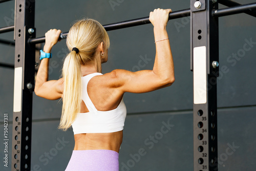 Unrecognizable woman doing pull ups on bar in fitness club