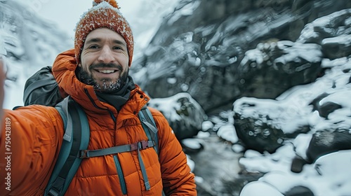 Joyful man in winter gear taking a selfie with snowy landscape.