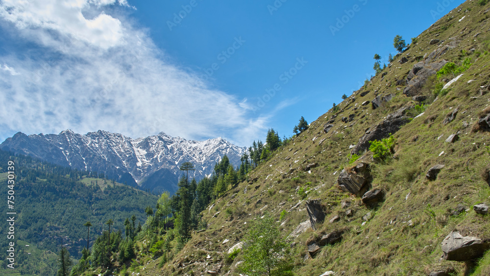 A vast landscape with clear skies, clouds, and snowy mountains.
