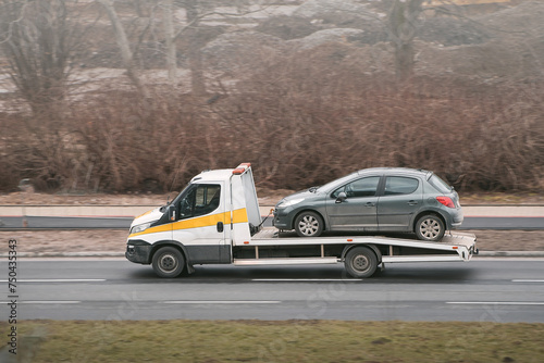 A tow truck helps a broken car on the highway. The car has been damaged by a collision and needs to be repaired