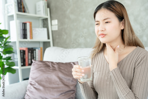 Asian woman put her hand on her neck due to a sore throat. female tonsillitis causes a inflammation. treated by taking water, taking antibiotics, consult a doctor, virus, corona virus, Influenza, flu.