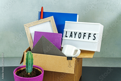 Cardboard box full of office stuff and personal items with lamp with text layoffs