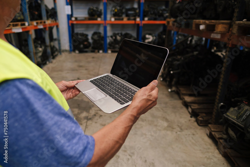 Senior auto mechanic holding laptop at warehouse photo