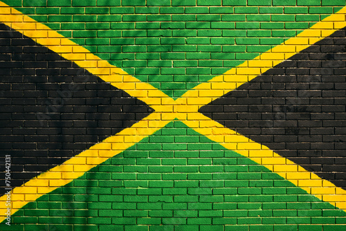 Jamaican flag painted on building brick wall with bare tree shadow cast on the surface