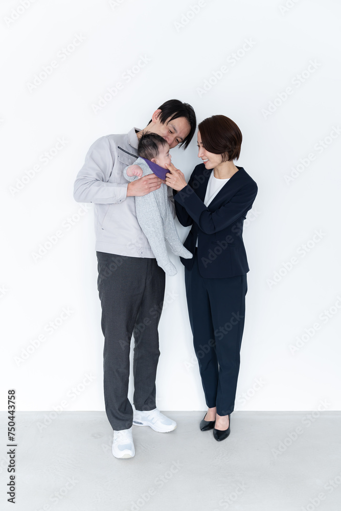 赤ちゃんを抱っこする作業着を着た男性とスーツを着た女性 赤ちゃんを抱っこする作業着を着た男性とスーツを着た女性