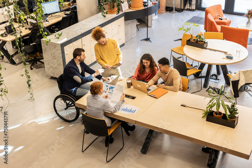 Businessman working with colleagues sitting at desk in office photo