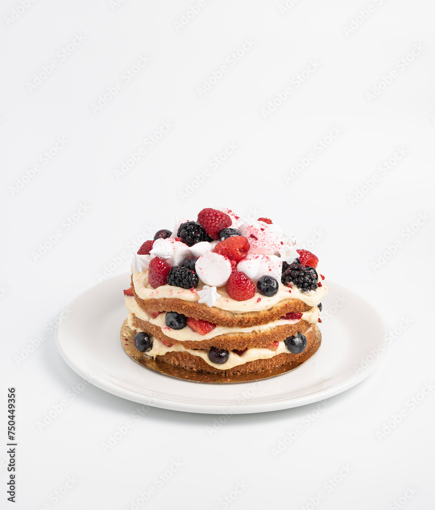 Cake layered with cream and decorated with fresh berries and marshmallows, on a white plate on an isolated background. Cake layered with cream and decorated with fresh berries and marshmallows, on a white plate on an isolated background.