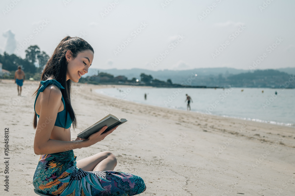 young woman reading a book relaxed on the beach